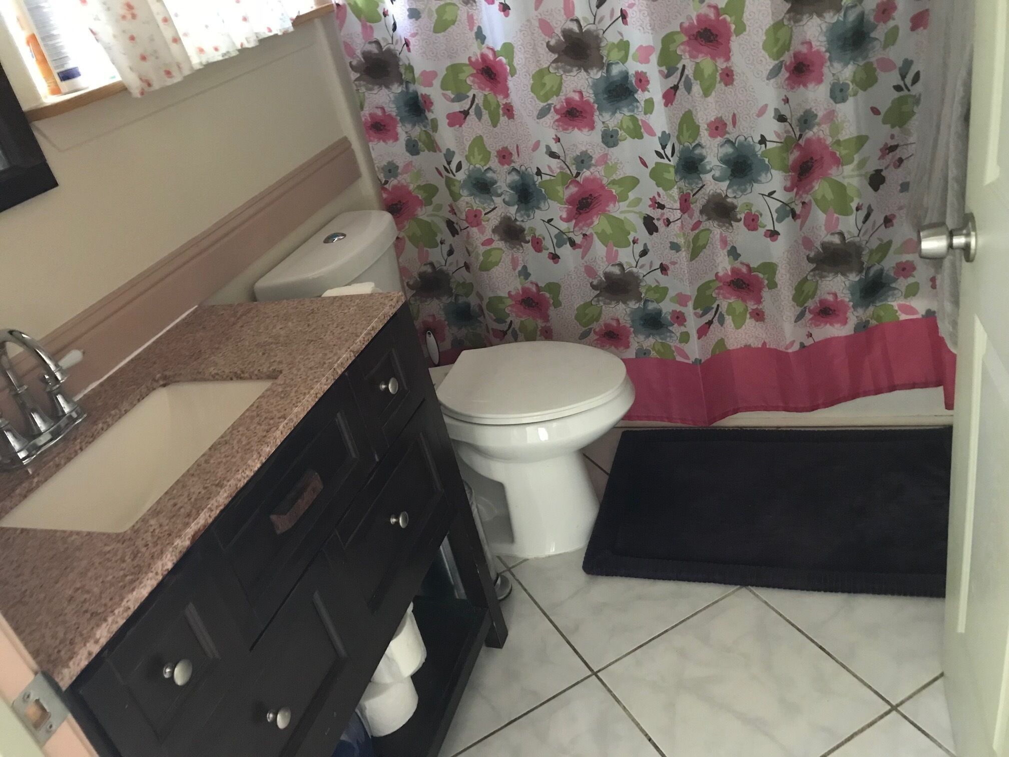A bathroom with a sink, toilet, and a shower curtain with a floral pattern.