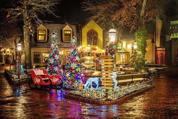 Un espacio exterior festivo con árboles de Navidad, una fuente y una zona de estar con la marca Coca-Cola.