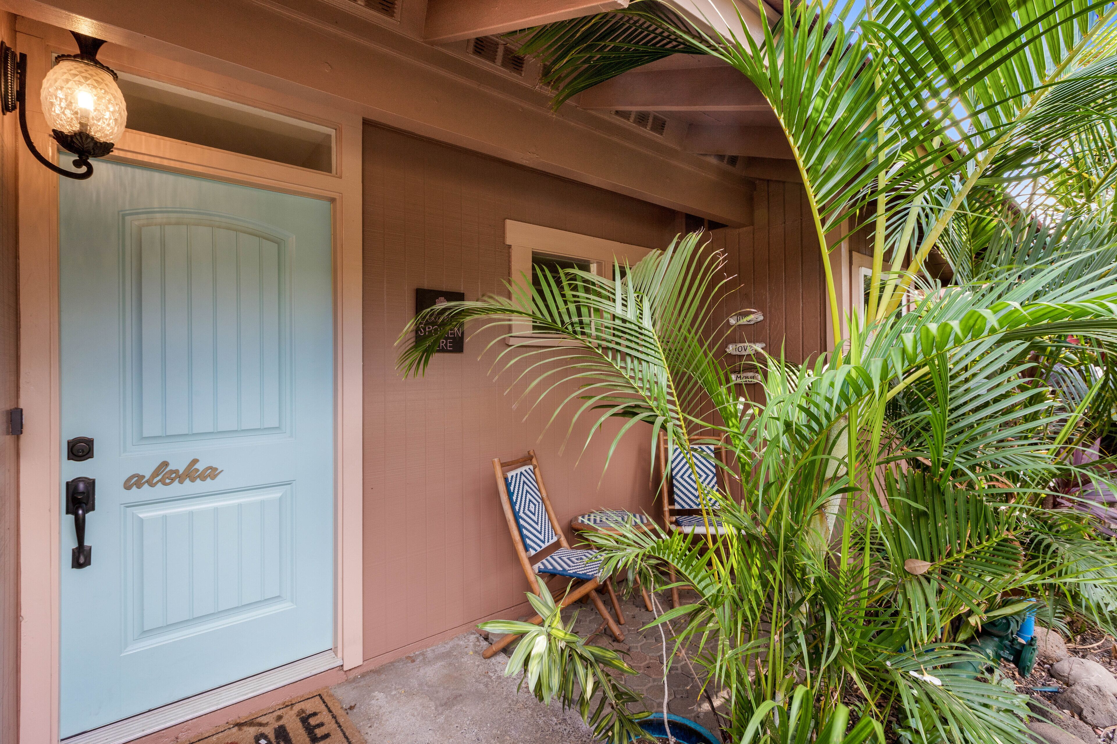 A light blue door with a handle and a keyhole, a small porch with two chairs, and a potted plant.