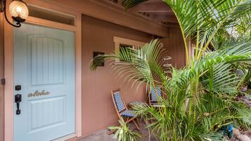 A light blue door with a handle and a keyhole, a small porch with two chairs, and a potted plant.