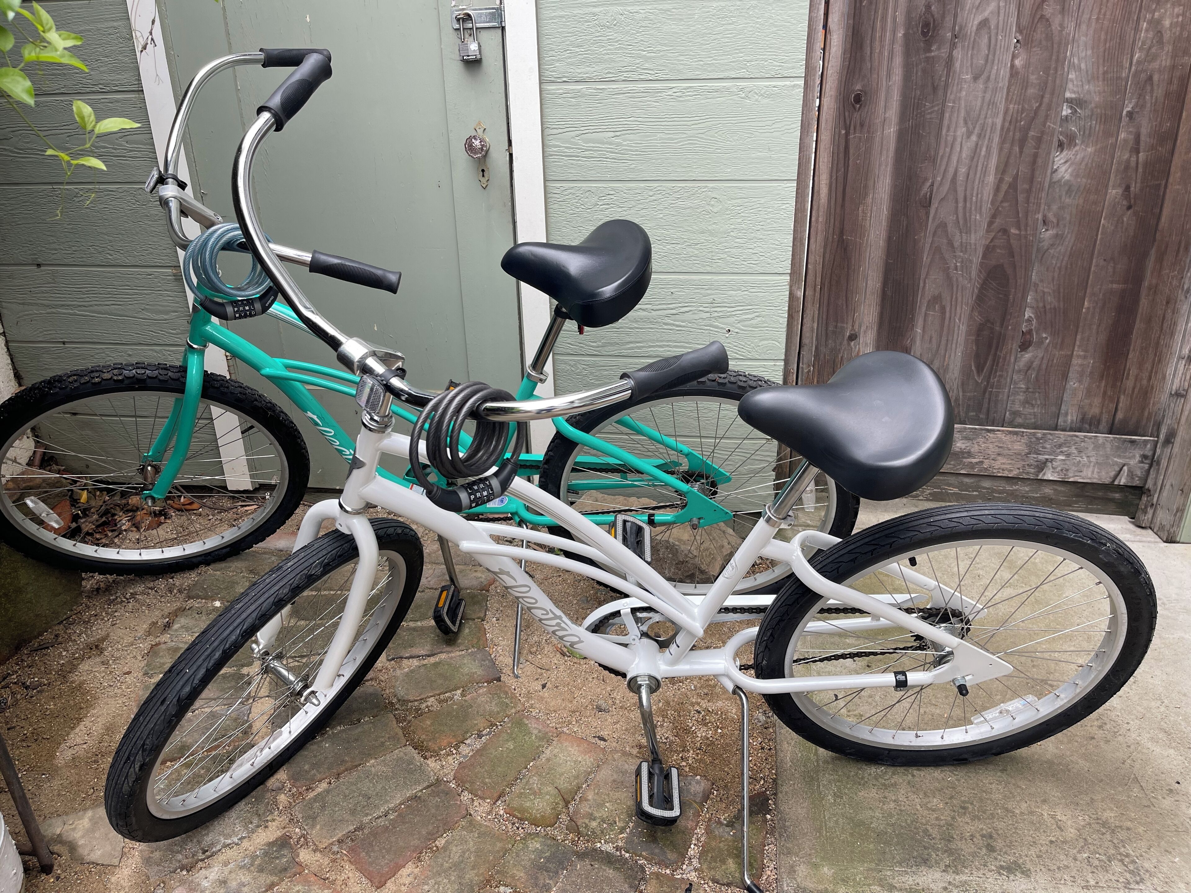 Una bicicleta turquesa y blanca estacionada sobre un área empedrada.