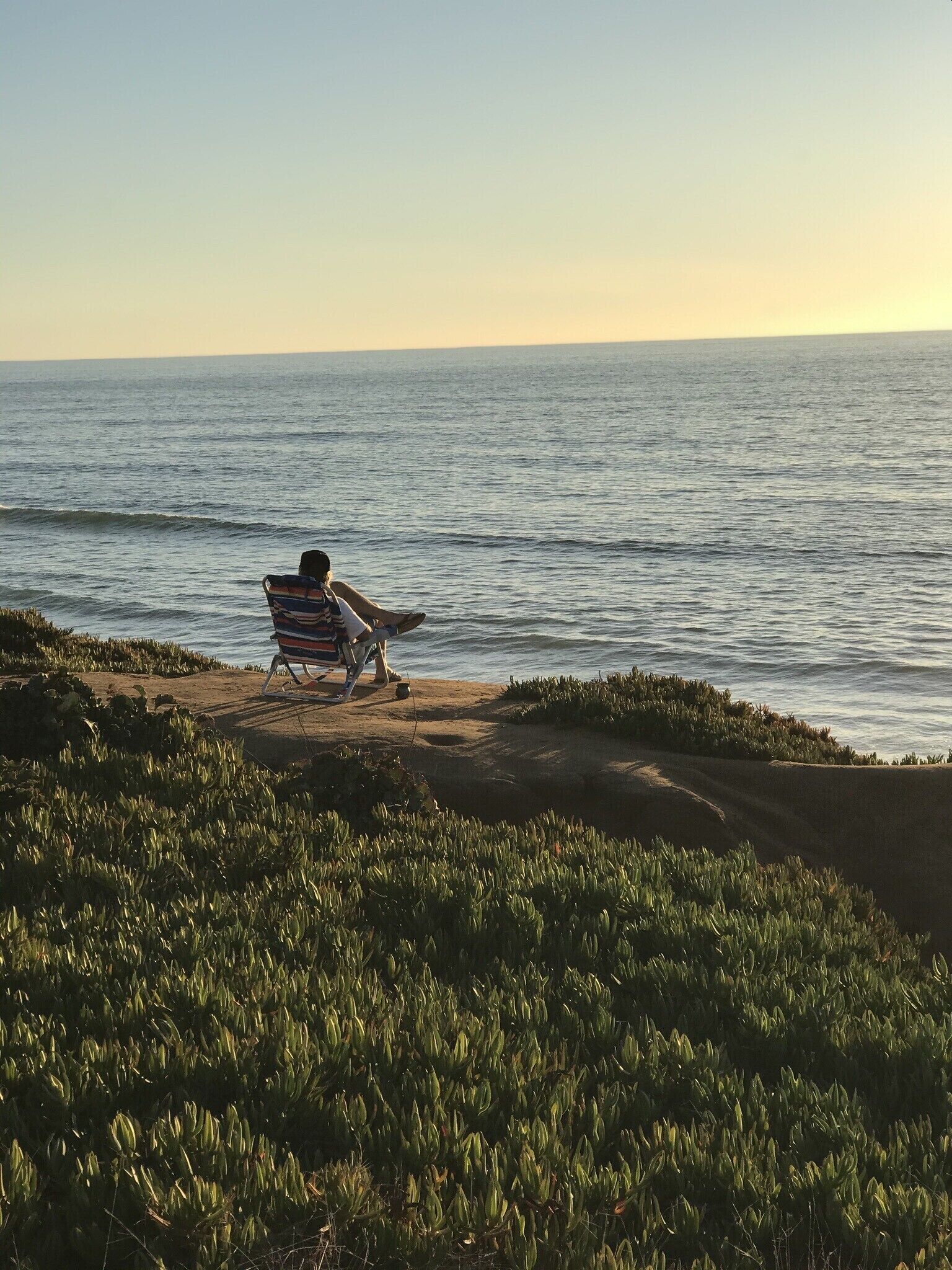 A person sitting on a beach chair facing the ocean.