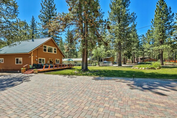 A lodge with a brick patio, wooden deck, and large windows.