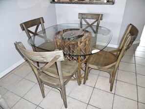 A round glass table with four wooden chairs.
