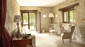A room with stone walls, a wooden door, a bed, two chairs, a lamp, and a window with a view of greenery. - Totally Private18th Century Stone Villa with 15mt heated Pool (Monte Castello di Vibio)
