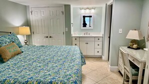 Un dormitorio con cama, cómoda, tocador con espejo y una puerta.