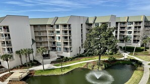 Un moderno complejo de apartamentos con varios balcones, un patio central con una fuente y un césped bien cuidado.