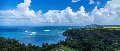 A golf course with a view of the ocean and a mountainous landscape.
