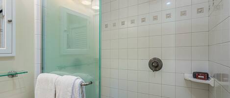 A bathroom with a glass shower enclosure, a white sink, and a towel rack.