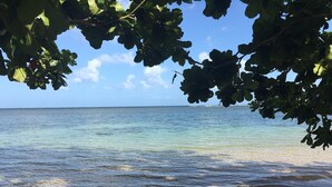 A beach with clear water and a view of the ocean.