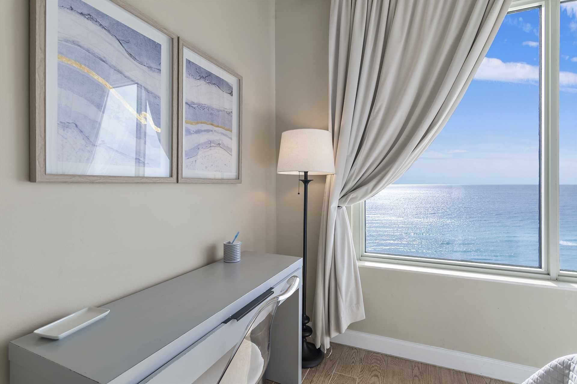 Een kamer met een bureau, een lamp en uitzicht op de oceaan.