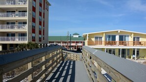 Un muelle de madera que lleva a un edificio con varios balcones y techo verde.