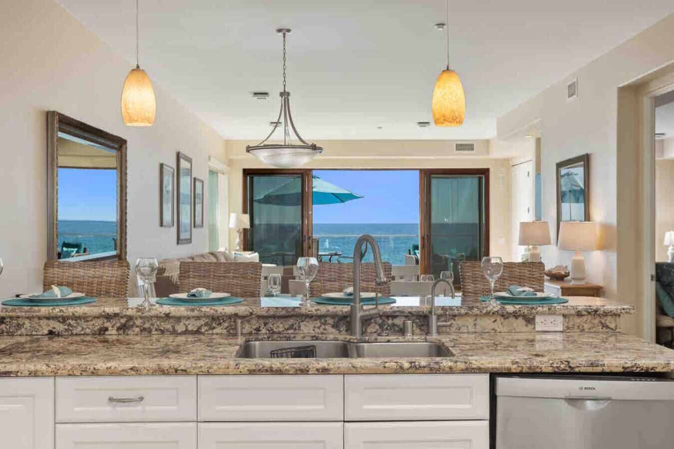 A modern kitchen with a large island, double sinks, and a view of the ocean.