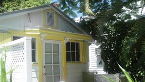 Una casa pequeña de un solo piso con un porche y una cerca blanca.