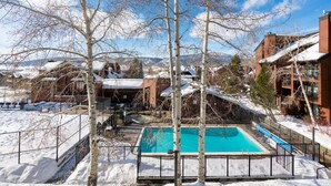 A swimming pool surrounded by snow-covered ground, with bare trees and buildings in the background. - Spacious 3-Bedroom + Loft Condo at Timber Run – Mountain Views, and Walkable to (Steamboat Springs)