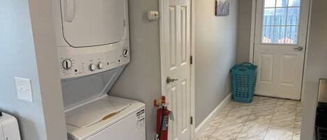 A laundry area with a washer and dryer, a fire extinguisher, a door, and a window.
