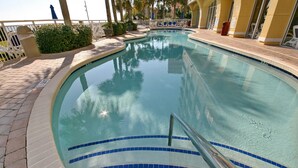 Une piscine dont le bord est revêtu de carrelage, dotée d’une rambarde métallique et bordée d’un chemin pavé.