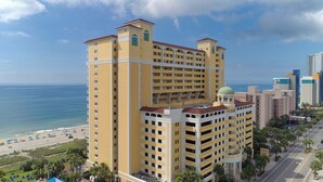 Un hôtel de grande hauteur doté de nombreux balcons, offrant une vue sur la plage et caractérisé par une imposante structure en forme de dôme.