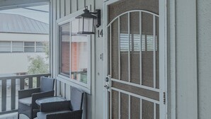 A porch with wicker furniture, a door with a screen, and a number '14' on the wall. - Light and bright beach retreat (Carlsbad)