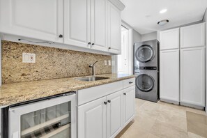 A kitchen with white cabinets, granite countertops, a stainless steel sink, a double oven, and a built-in washer and dryer.