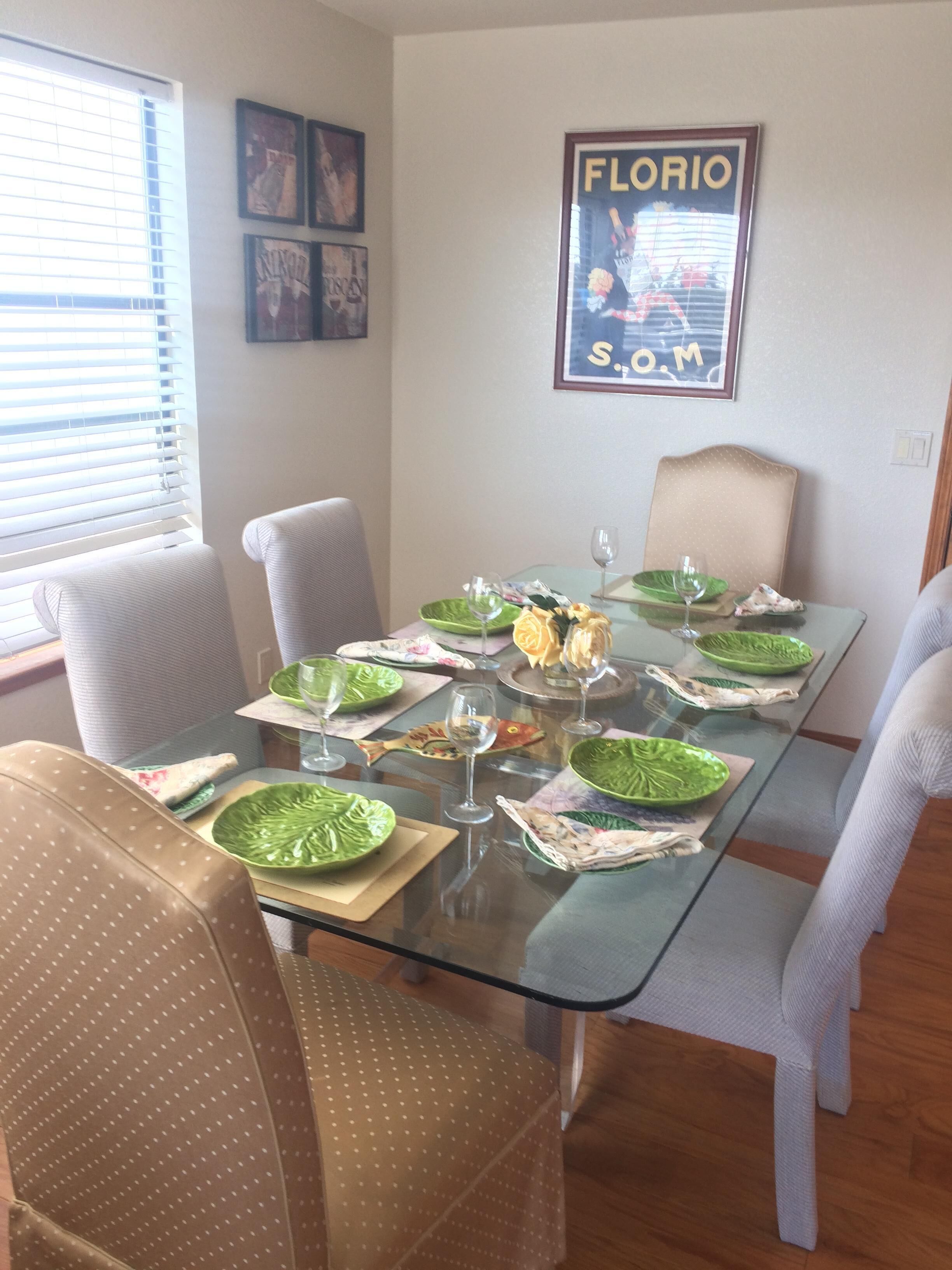 Zona pranzo con tavolo in vetro, piatti verdi e sedie.