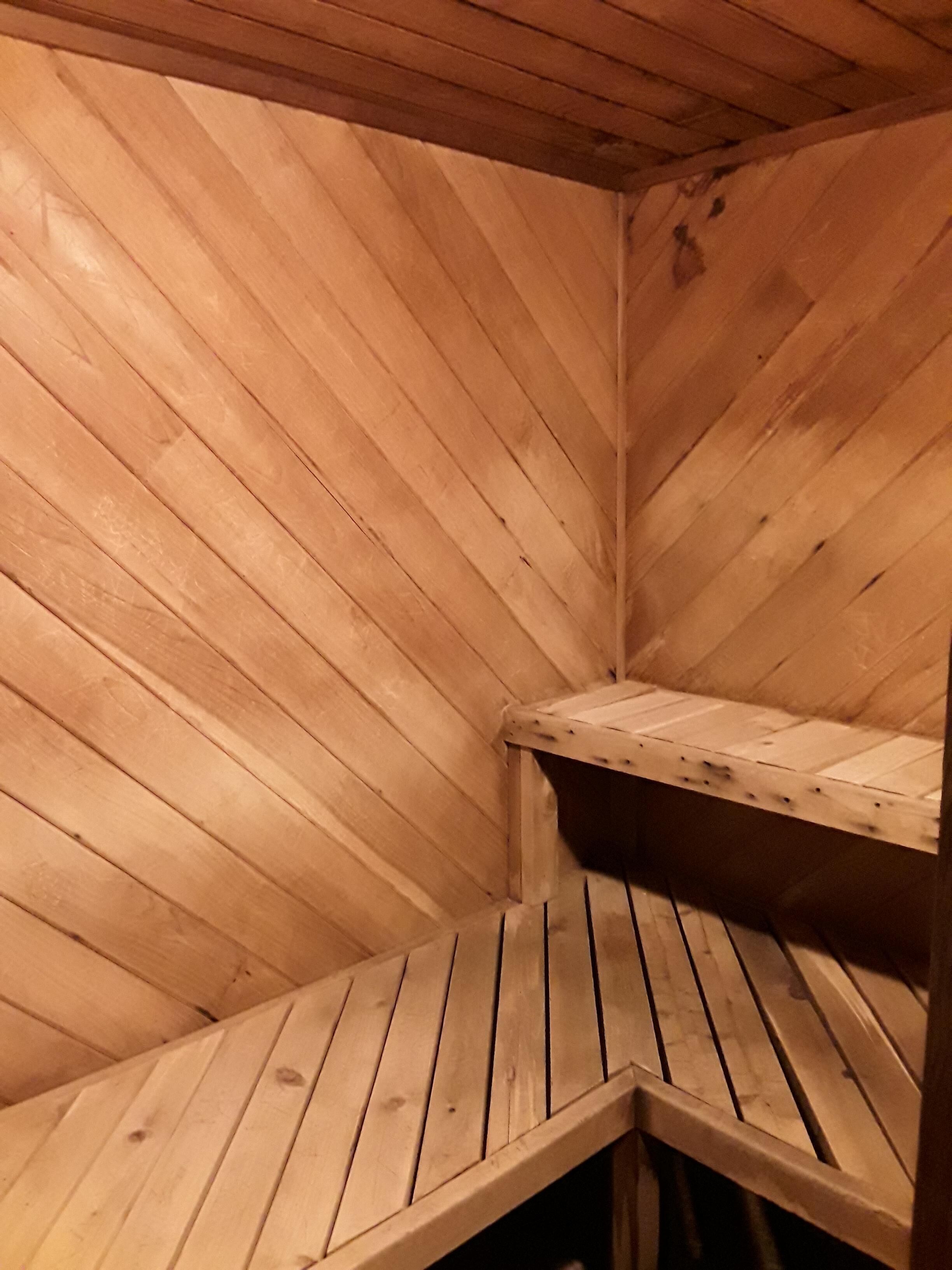 A wooden sauna with slatted benches and a corner bench.