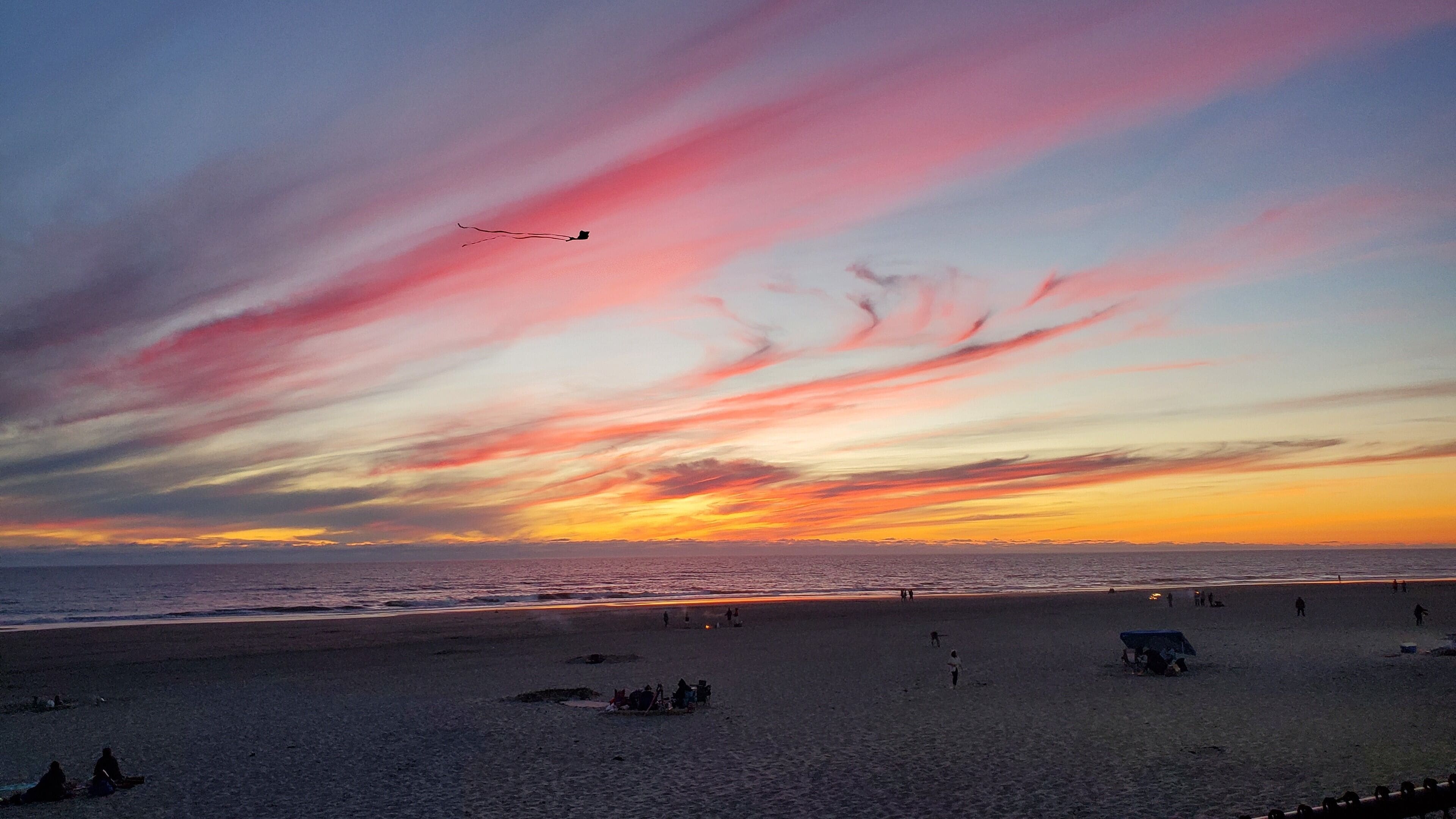 Una playa con gente y un atardecer.