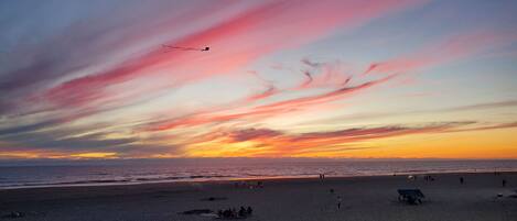 Una playa con gente y un atardecer.