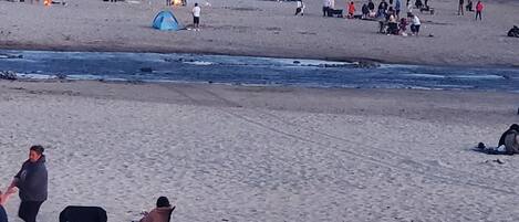 Una playa con gente, tiendas de campaña y algunas sillas.