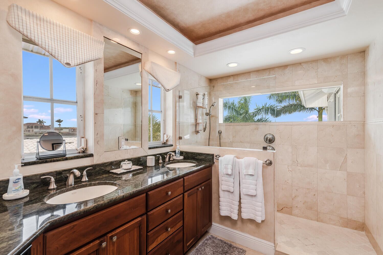 Une salle de bain moderne avec deux lavabos, un grand miroir et une douche à l’italienne.