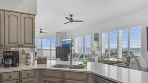 A modern kitchen with a built-in dishwasher, a coffee maker, and a large window overlooking the ocean. - Crystal View301 3 Bedrooms | 3 Baths | Accommodates 12 | Pet Friendly (Miramar Beach)