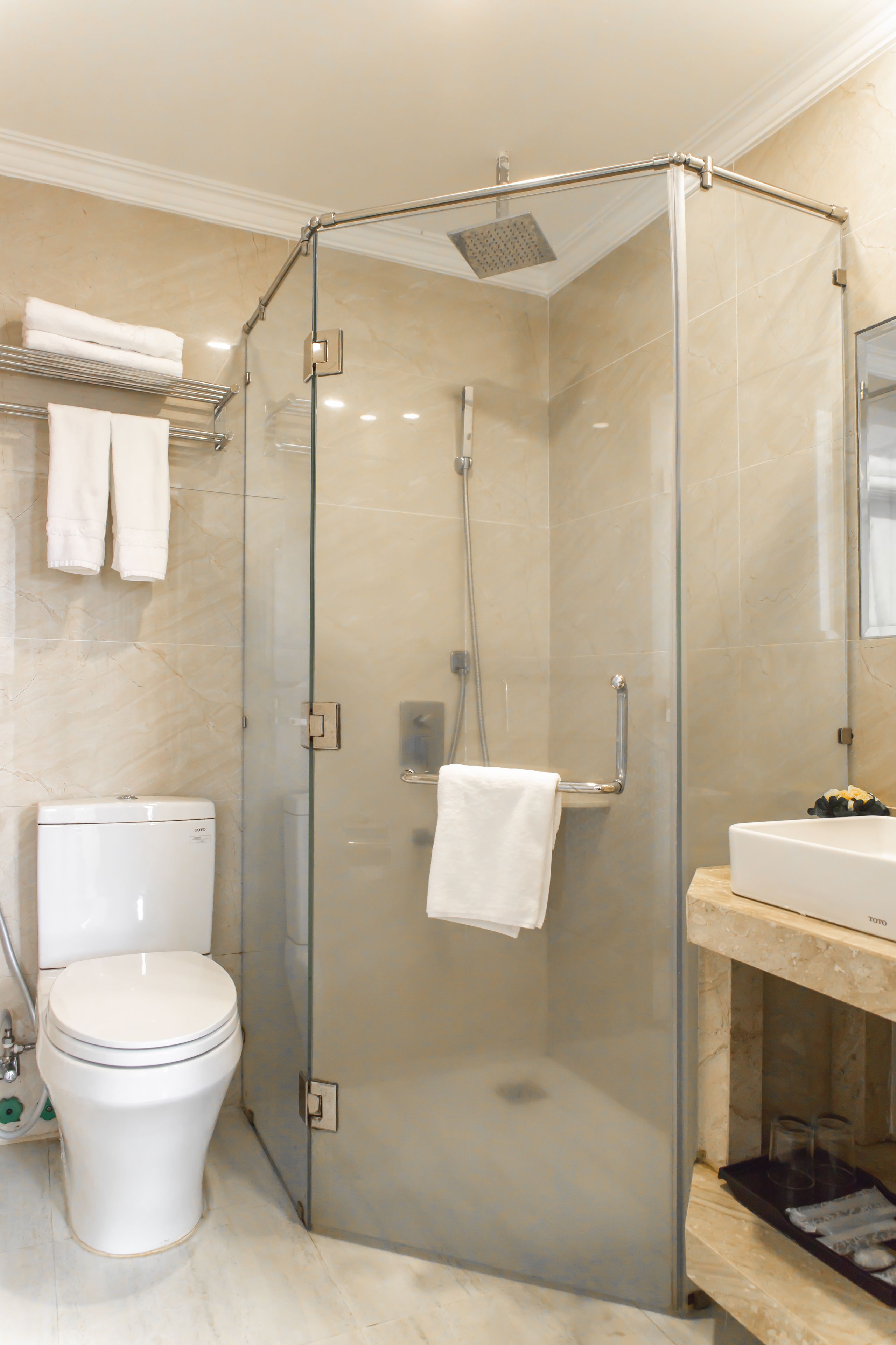 A modern bathroom with a glass-enclosed shower, a toilet, and a sink with a marble countertop.