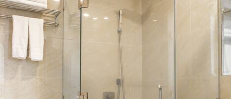 A modern bathroom with a glass-enclosed shower, a toilet, and a sink with a marble countertop.