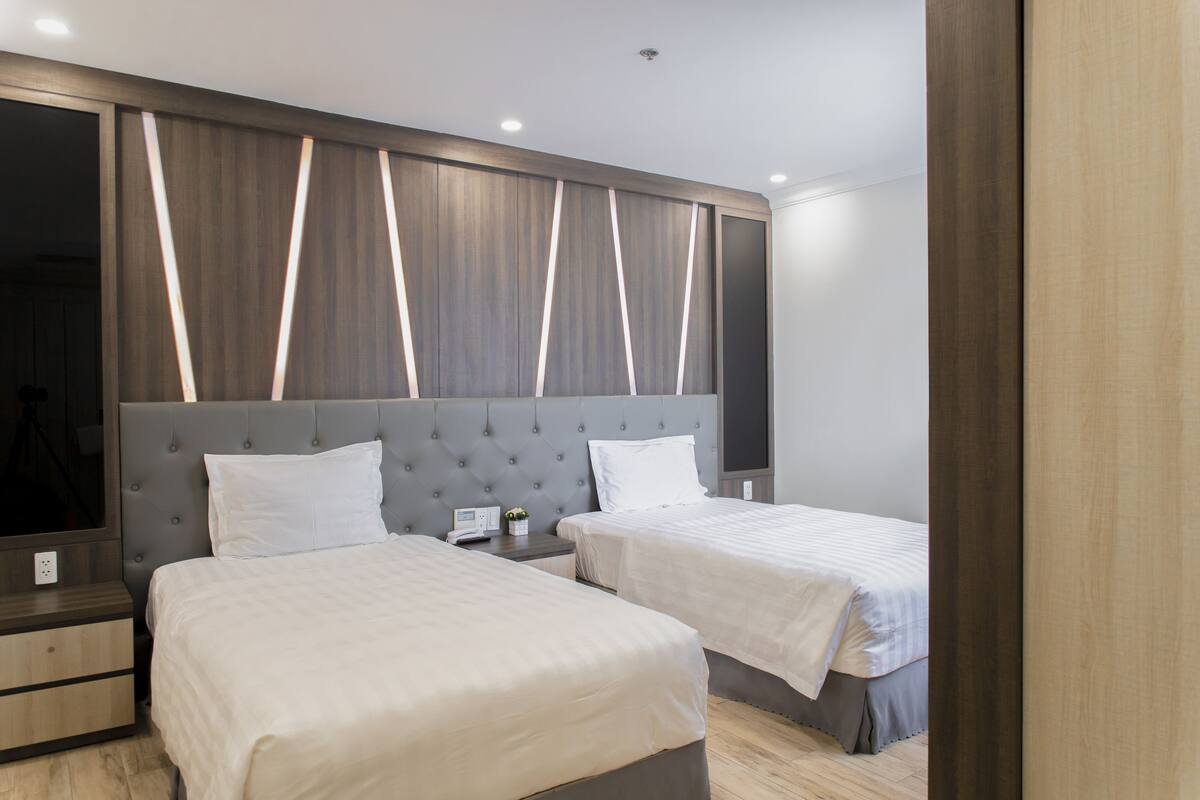 A hotel room with two beds, a large mirror, and a modern wall design.