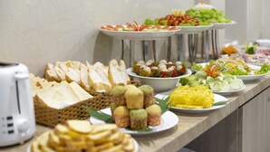 A buffet with various food items including bread, fruits, and salads. - Seven Seas Hotel and Apartment (Nha Trang)