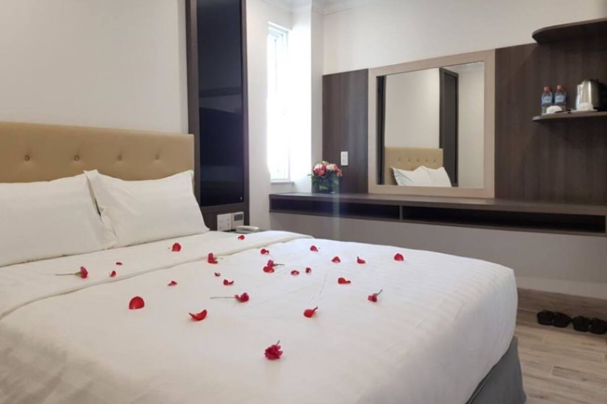 A hotel room with a large bed, a mirror, and a shelf with toiletries.
