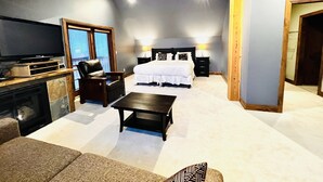 A bedroom with a large bed, a TV, a desk, and a chair.