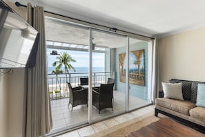 A balcony with a view of the ocean, a dining table with chairs, and a sofa with cushions. - Direct Ocean View from Your Condo-No Contact Check-In (Key West)