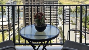 A balcony with a glass table, chairs, and a flower vase. - View Condo with Free Parking, Pool, Hottub, Sauna, Tennis Court and More (Honolulu)