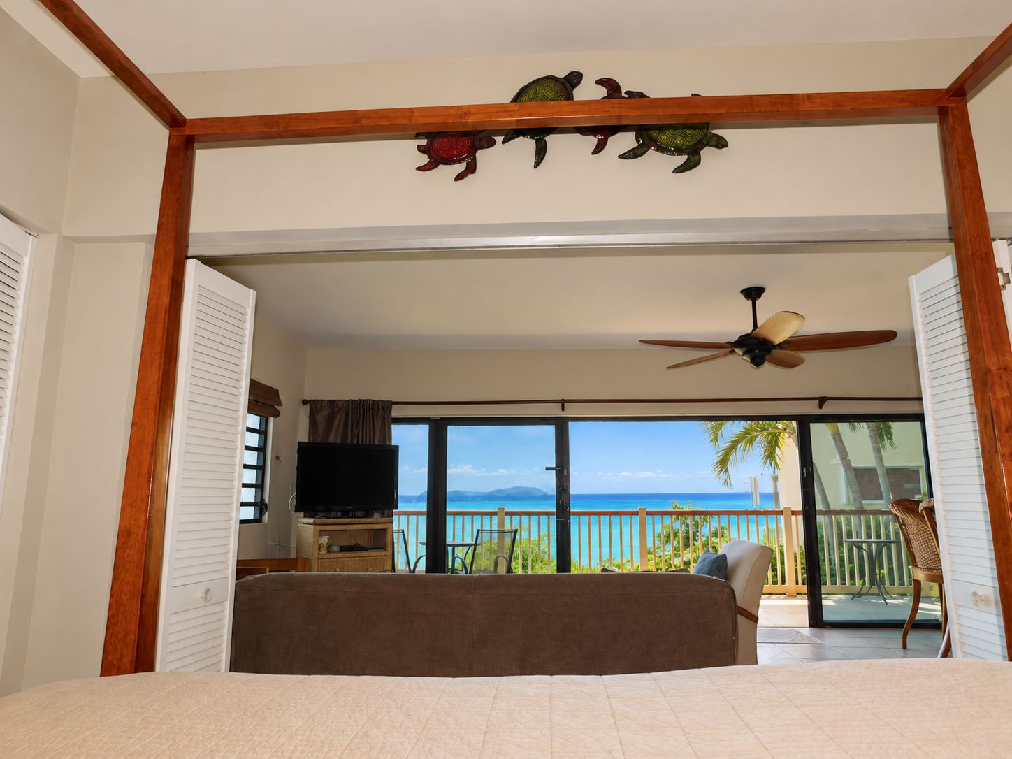 A bedroom with a bed, a television, and a view of the ocean.