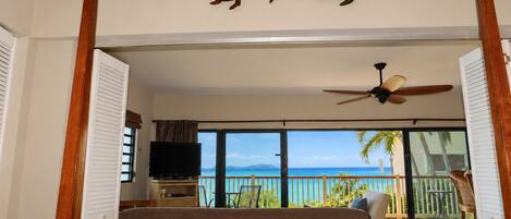 A bedroom with a bed, a television, and a view of the ocean.