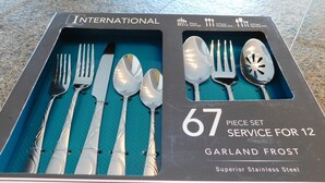 A box containing a 67-piece stainless steel service set for 12, including forks, knives, and spoons, labeled as 'GARLAND FROST' and 'Superior Stainless Steel'.