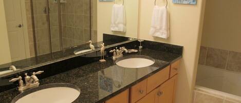 A bathroom with two sinks, a large mirror, and a shower area.