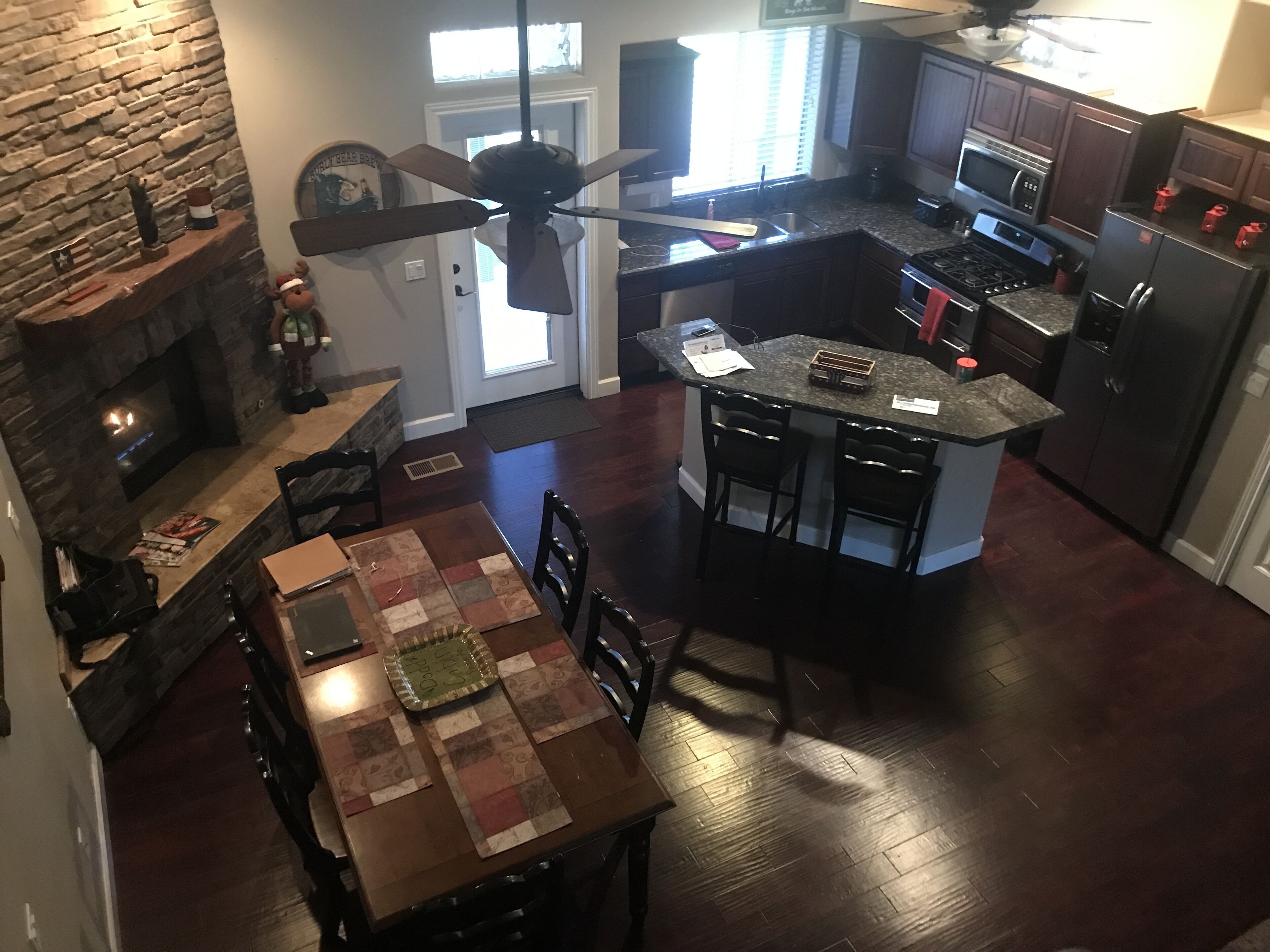 Una cocina con chimenea de piedra, un comedor con mesa y sillas, y un ventilador de techo.