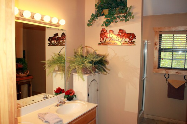 A bathroom with a large mirror, a sink, and a window.