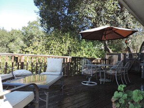 A wooden deck with outdoor furniture, including chairs and a table, under a large umbrella.