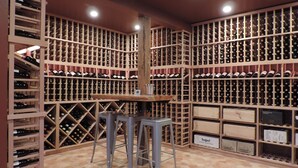 Une cave à vin avec des étagères en bois et des tabourets.