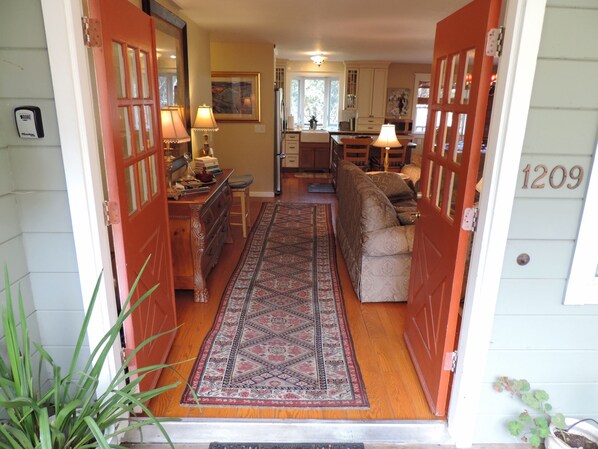 A cozy interior with a wooden floor, a patterned rug, a sofa, and a dining area.
