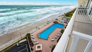 A hotel with a pool, beach view, and a road with a van. - Spectacular views, direct oceanfront, separate bedroom ! (Daytona Beach)