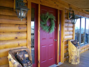 A wooden cabin with a red door, two wooden benches, and a wreath on the door. - Potomac Overlook  Log Cabin / WIFi at 12364 Petersburg Pike, Upper Tract,WV . (Upper Tract)
